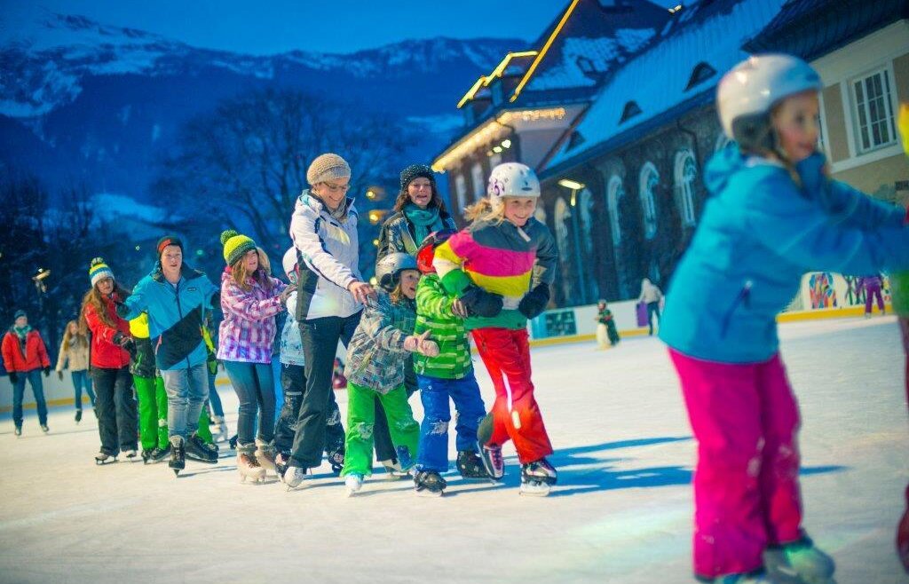 Děti a dospělí v podvečer na kluzišti u Alpenareny v Bad Hofgasteinu