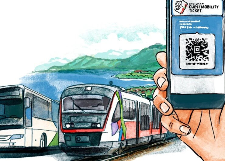Ruka držící telefon s jízdenkou pro hosty, v blízkosti autobusu a vlaku u malebného jezera a hor.