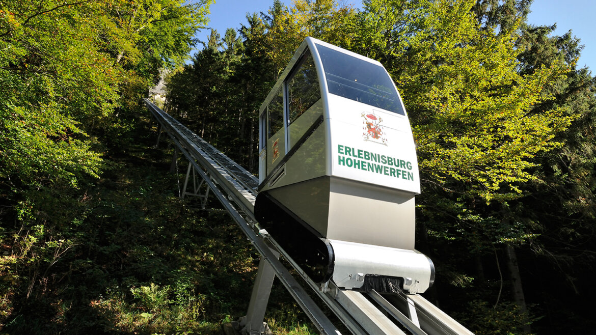 Kabina stoupá po strmém zalesněném svahu k Hradu Hohenwerfen.