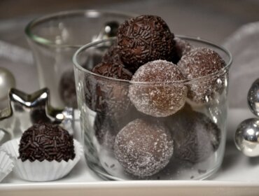 DSC_0021-001 Čokoládové kuličky obalené cukrem a posypané ve skleněné míse, se slavnostními dekoracemi poblíž.