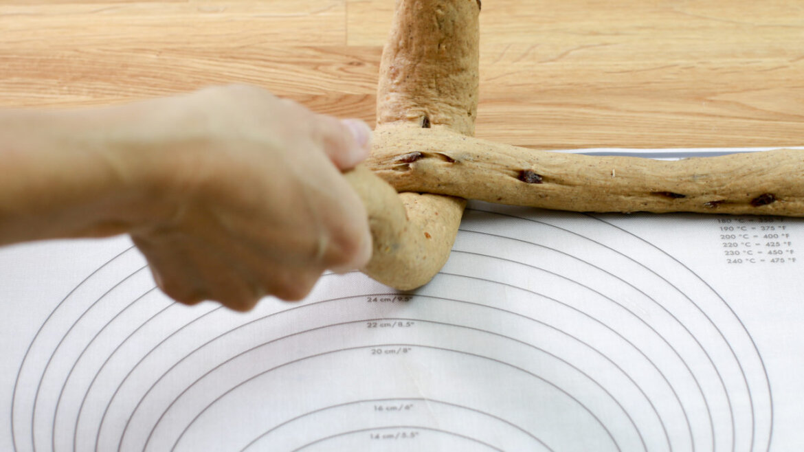 © Anke Eder Ruka na kruhové měřicí podložce stočí dva prameny chlebového těsta. (Zvětšený pohled)