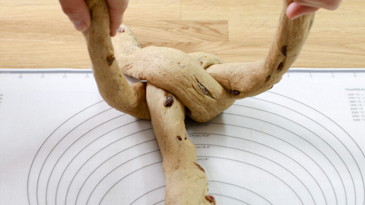 © Anke Eder Ruce pletou na podložce tři prameny těsta s rozinkami. (Zvětšený pohled)