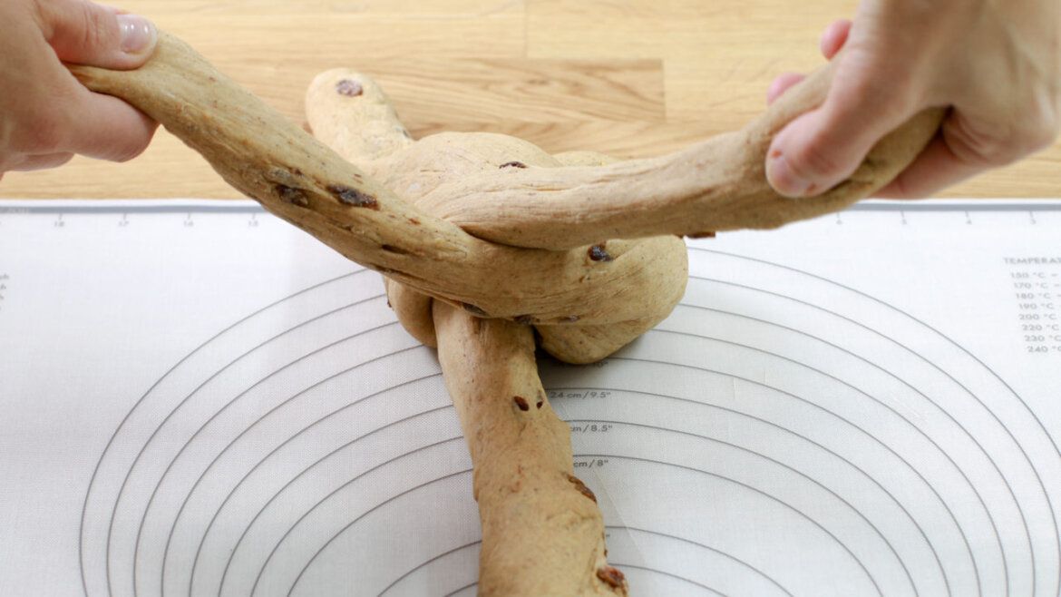 © Anke Eder Dvěma rukama upleteme tři prameny těsta na podložce na pečení s vodítky. (Zvětšený pohled)