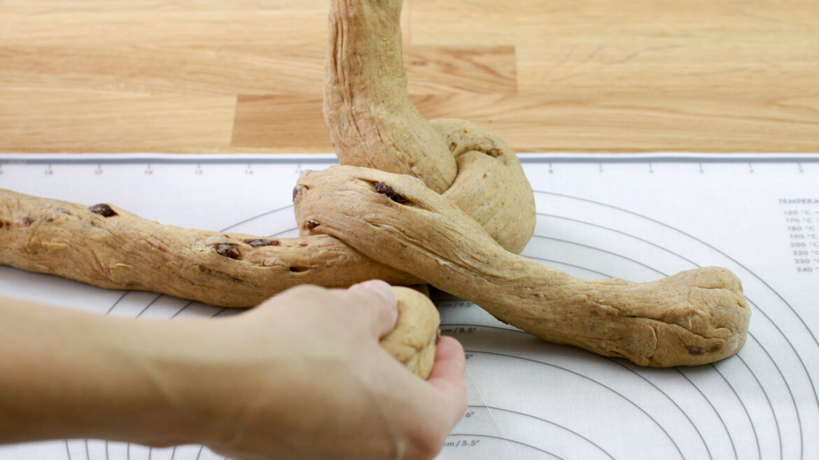 © Anke Eder Ruce pletou na podložce tři prameny těsta s rozinkami. (Zvětšený pohled)