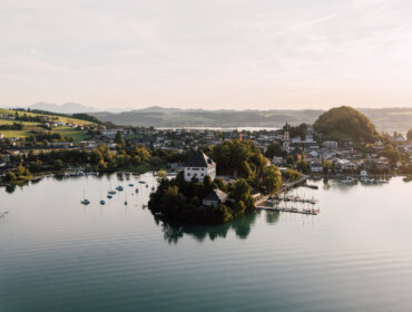 Letecký pohled na malý ostrov v Salcburské zemi jezer, obklopený klidným jezerem a malebným městečkem.