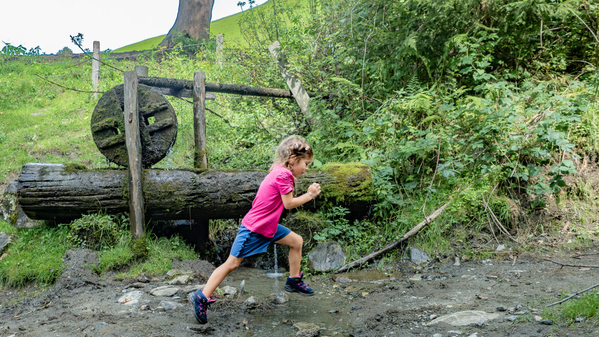 Dítě si hraje a běhá v přírodě v oblasti Piesendorf a Niedernsill, obklopené loukami a stromy (Zvětšený pohled)