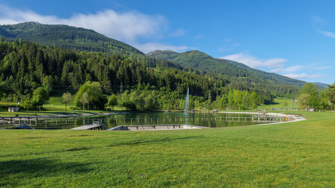 Pohled na přírodní koupaliště v Niedernsillu s čistou vodou, loukami a okolní přírodou (Zvětšený pohled)