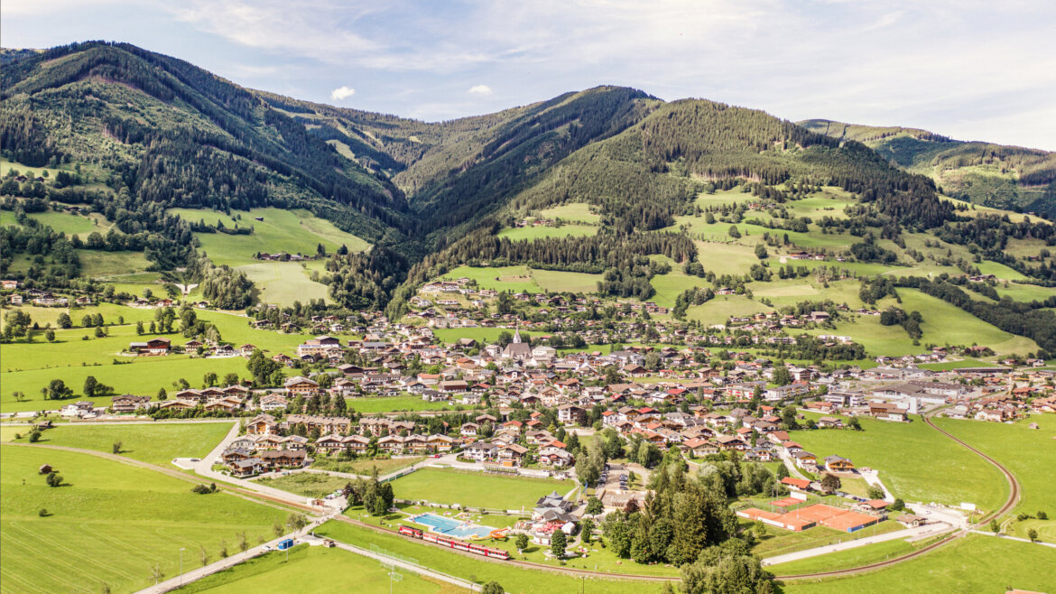 Městečko Piesendorf s pinzgauskou lokálkou a koupalištěm Hinkelsteinbad (Zvětšený pohled)