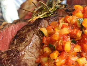 Steak propečený na „medium-rare“ s přílohou nakrájené zeleniny v rajčatové omáčce, podávaný na talíři s modrobílým vzorem.