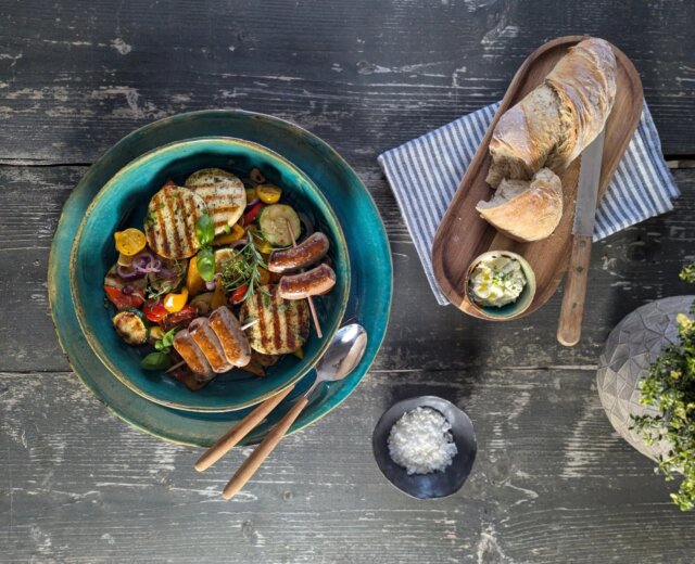 Grillgemüse, Grillkäse und Grillwürstl©Salzburger Agrar Marketing-Martina Höfelmaier Grilované klobásy a zelenina v misce, chléb a máslo na prkénku, sůl v malé misce.