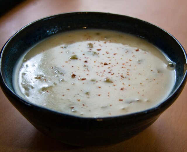 cremige Kartoffelsuppe in einer Schale Na dřevěné desce stojí tmavá miska krémově bílé bramborové polévky, posypaná kořením.