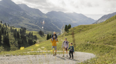 Familie med to børn på vandretur på en bjergsti tæt på skiløjperne i Obertauern.