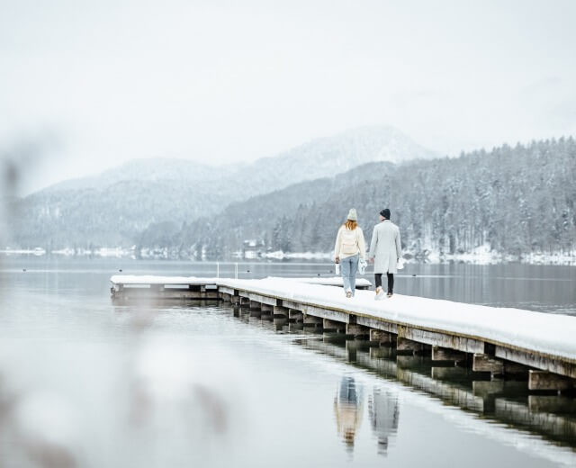 Et par går på en kaj i sneen.