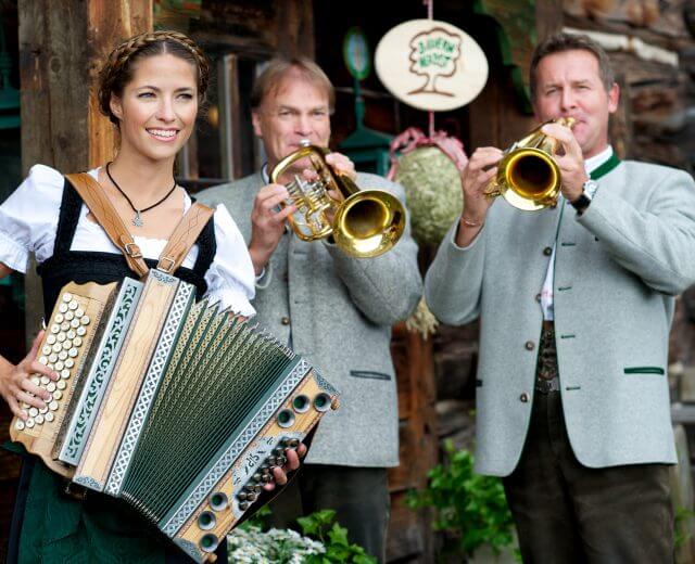 Bauernherbst Musikanten Drei Personen in traditioneller österreichischer Kleidung spielen Akkordeon und Trompeten bei einem rustikalen Bauernherbstfest.
