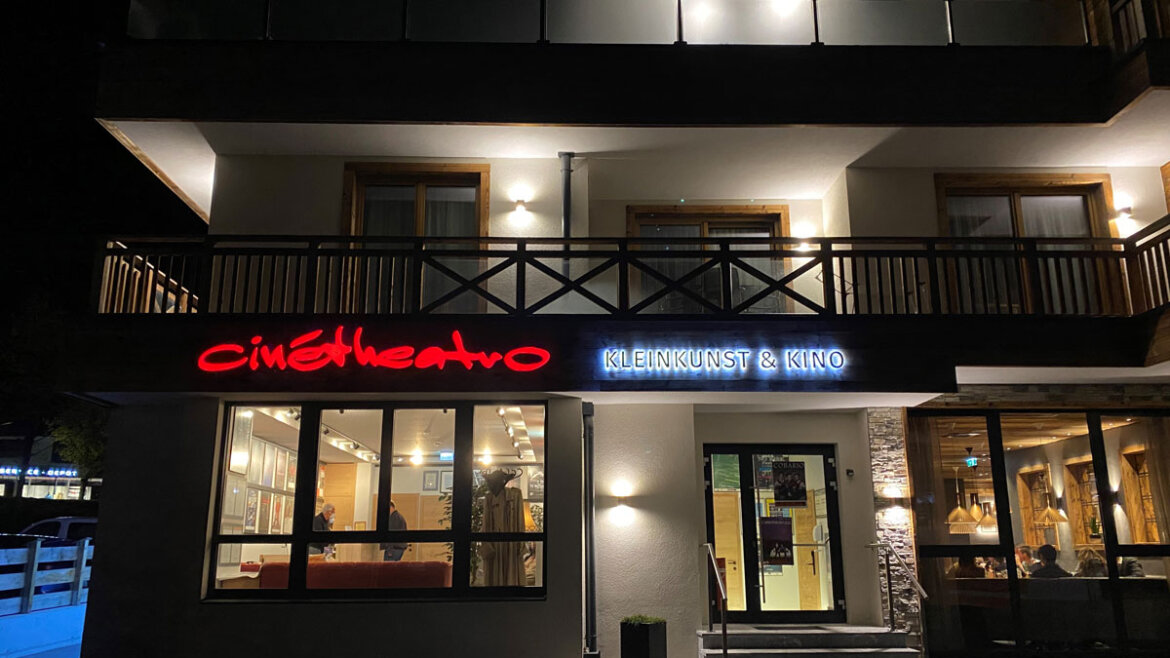 Nachtansicht des Cinetheatros in Neukirchen mit Schildern mit der Aufschrift cinétheatro und Kleinkunst & Kino über dem Eingang. (vergrößerte Ansicht)