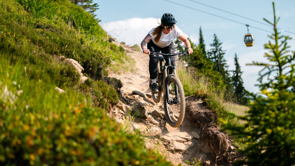 Mountainbiken bergab auf einem felsigen Weg in Saalbach Hinterglemm, mit einer Seilbahn im Hintergrund. (vergrößerte Ansicht)