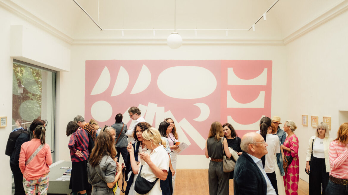 Menschen versammeln sich in einer Kunstgalerie im Gasteinertal und unterhalten sich, während sie ein großes abstraktes Wandgemälde in Rosa und Weiß bewundern. (vergrößerte Ansicht)