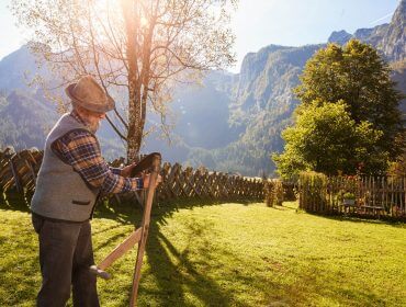 Ein Bauer schärft seine Sense zum Mähen.