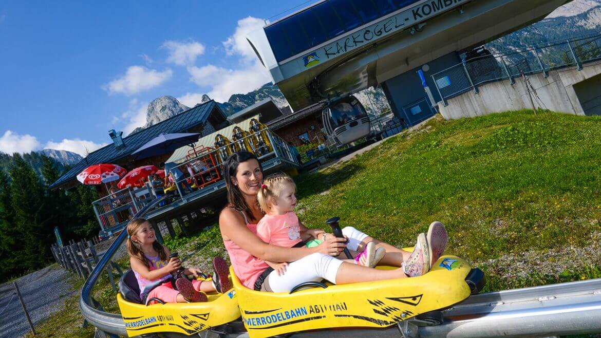 Mutter mit Kind in der gelben Sommerrodelbahn an der Bergstation