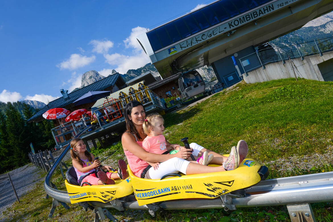 Mutter mit Kind in der gelben Sommerrodelbahn an der Bergstation
