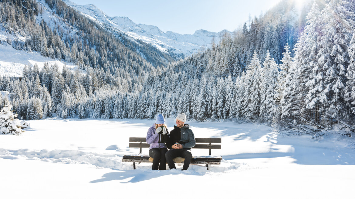 Ein Pärchen auf einer Bank in verschneiter Landschaft