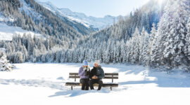 Auszeit in der Nationalpark-Region mit Blick auf Hohe Tauern (c) Ferienregion Nationalpark Hohe Tauern – Mathäus Gartner (25) Ein Pärchen auf einer Bank in verschneiter Landschaft