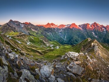 Edelweißspitze_Großglockner Hochalpenstrasse (c) Ferienregion Nationalpark Hohe Tauern – van Schaik Kurvenreiche Bergstraße durch grünes Tal in der Ferienregion Nationalpark Hohe Tauern bei Sonnenaufgang.