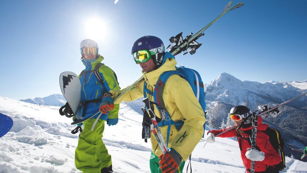 Drei Freerider, davon zwei Skifahrer und ein Snowboarder, steigen gemeinsam zum Freeriden auf