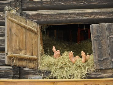 Zwei Personen liegen barfuß im Heu - zu sehen sind nur die nackten Füße im geöffneten Heubodenfenster
