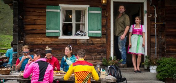 Gäste vor der Almhütte mit Wirt