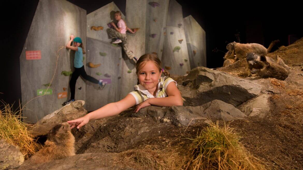 Kinder im überdimensionaklen Murmeltierbau, im Hintergrund eine Kletterwand
