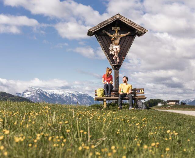 Pilgern in Eugendorf © SalzburgerLand Tourismus, Michael Groessinger, Pilgern im SalzburgerLand Pilgern,Pilgern im SalzburgerLand,Sommer,Salomon,Paar,Pärchen,Rucksack,Landschaft,wandern,Weg,Jakobsweg,Blumenwiese,Blumen,Feld,Wetterkreuz,Pause