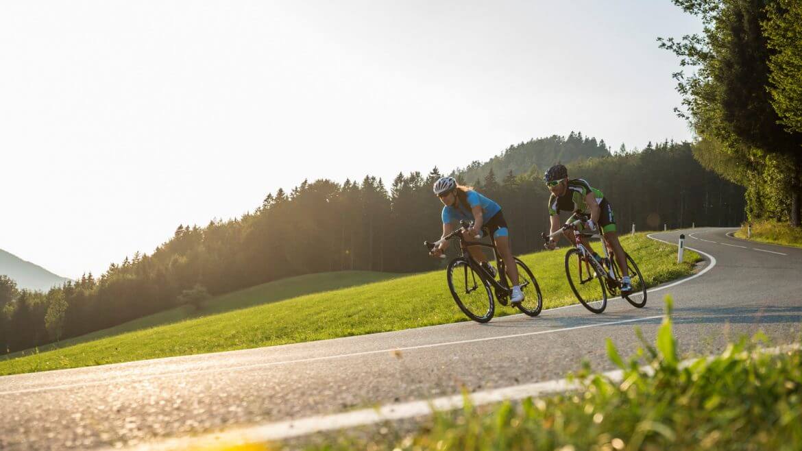 Zwei Radfahrer fahren im Sonnenuntergang bergab um die Wette