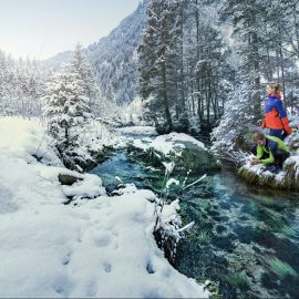 Zwei Läufer erfrischen sich am glasklaren Bach in einem verschneiten Wald