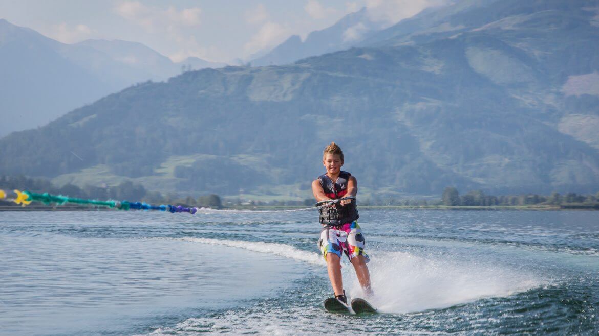 Junge fährt auf Wasserski an einem schönen Tag über einen See im SalzburgerLand.