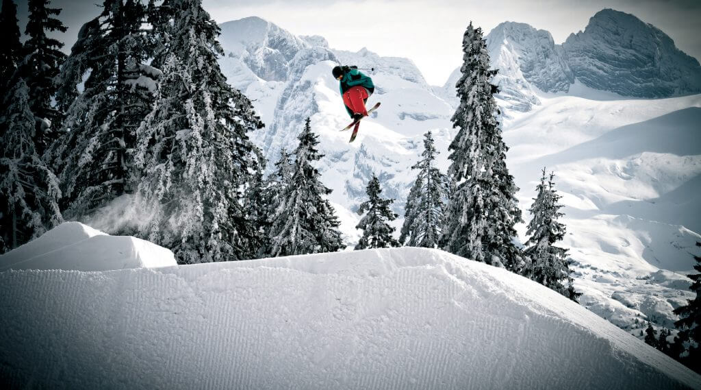 Freestyler auf Skiern hoch in der Luft in tief verschneiter Landschaft