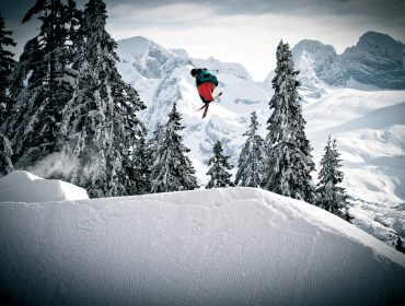 Freestyler auf Skiern hoch in der Luft in tief verschneiter Landschaft