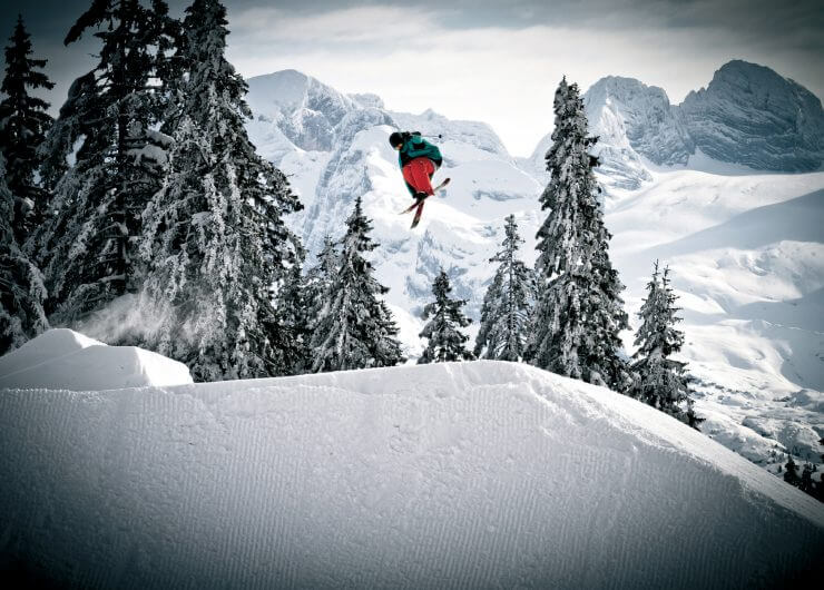 Freestyler auf Skiern hoch in der Luft in tief verschneiter Landschaft