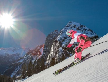 Skifahrer im rot-weißen Overall auf der frisch präparierten Piste