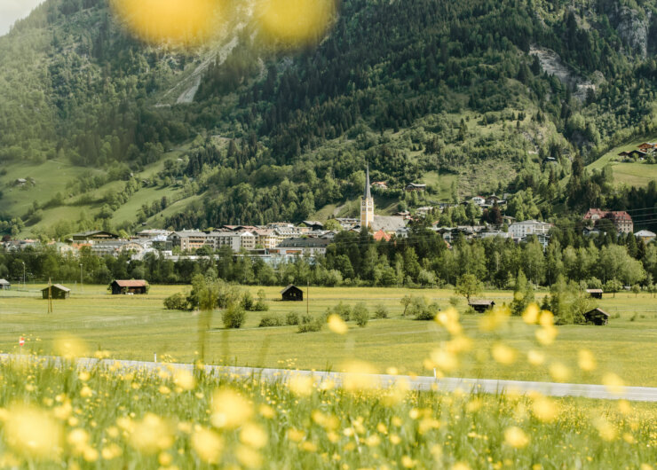 Sommer in Bad Hofgastein Blick auf das Dorf Bad Hofgastein und den Kirchturm, eingebettet in grüne Wiesen und bewaldete Berge.