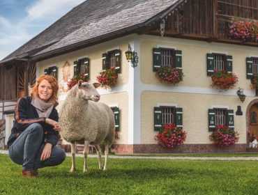 Mädchen mit Schaf vorm Bauernhof