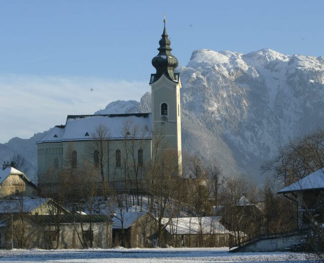 Die Schnee bedeckte Kirche von Wals-Siezenheim - im Hintergrund der Untersberg