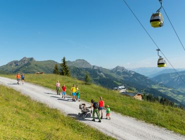 Wandern mit der Sommerbergbahn in Großarltal Wanderer auf einem Bergpfad im Großarltal, mit Seilbahnen, malerischen Hügeln und blauem Himmel im Hintergrund.