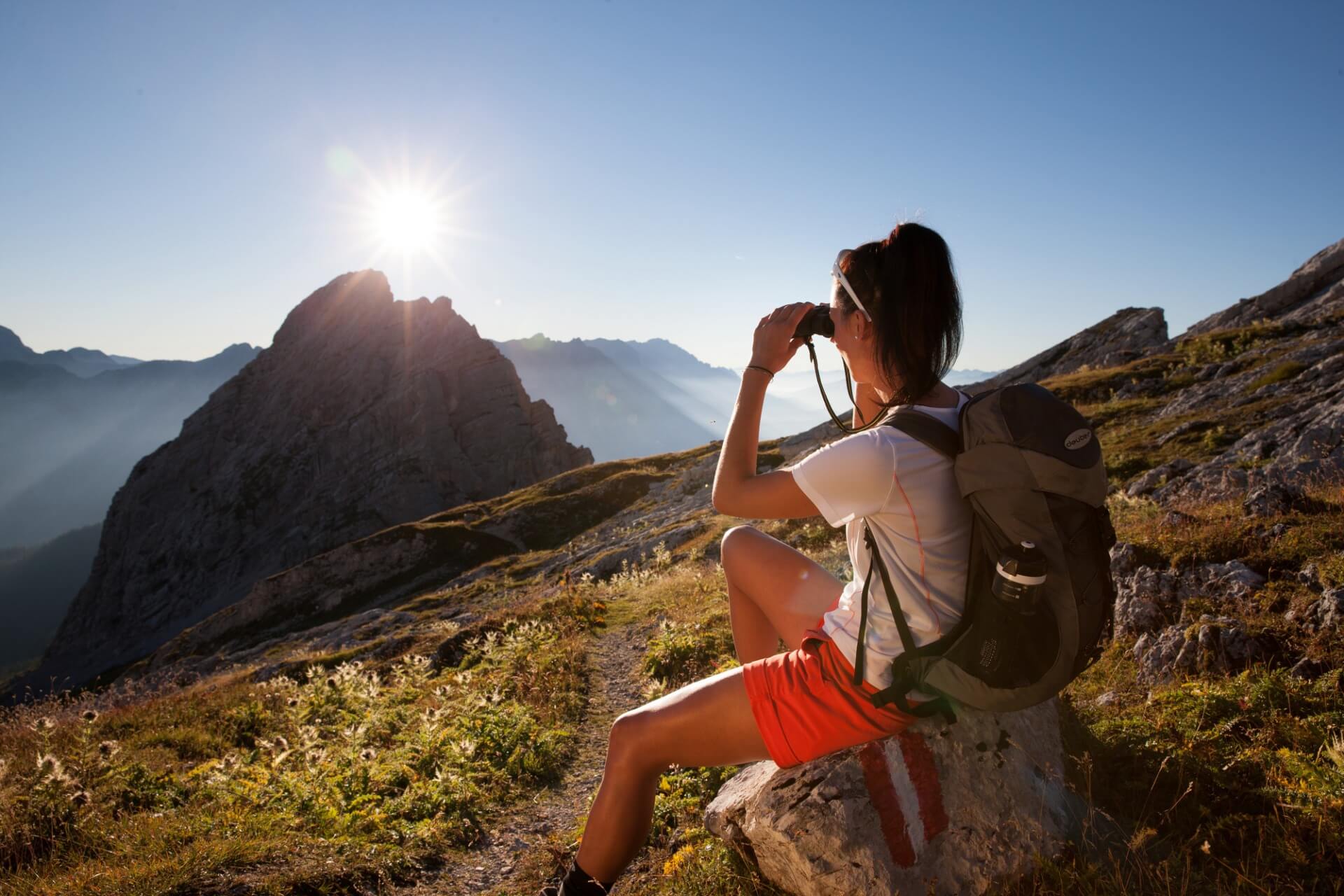 Wanderer beobachtet Sonnenuntergang am Salzburger Almenweg