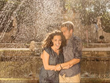Ein lächelndes Paar steht zusammen unter einer Springbrunnengischt im Garten des wasserreichen österreichischen Salzburgerlandes.