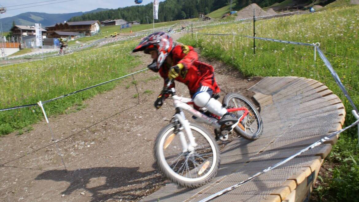 Kleiner Bike-Profi in voller Montur inklusive Helm auf der Downhill-Strecke