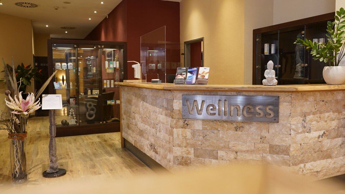 (c) Aqua Salza Empfangsbereich des Aqua Salza Wellness Spa mit Holztisch, Pflanzen, Broschüren und beruhigendem Dekor. (vergrößerte Ansicht)