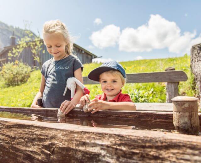 Kinder am Brunnen in der Almenwelt Lofer.