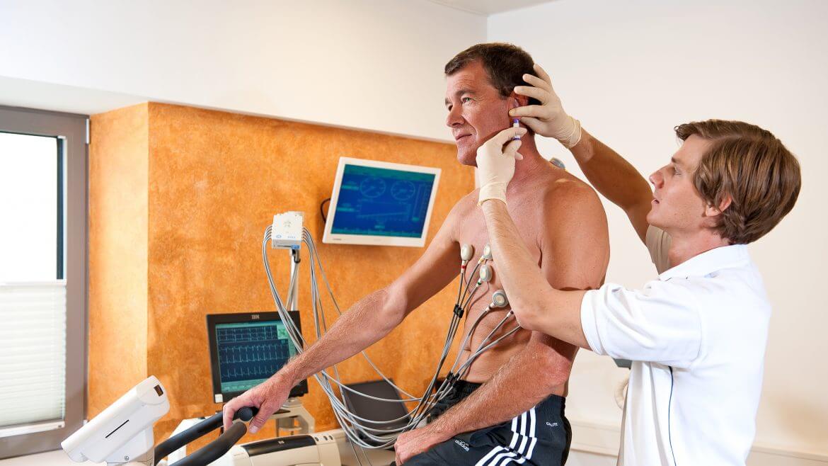 Mann auf dem Ergometer erhält Spritze von Arzt