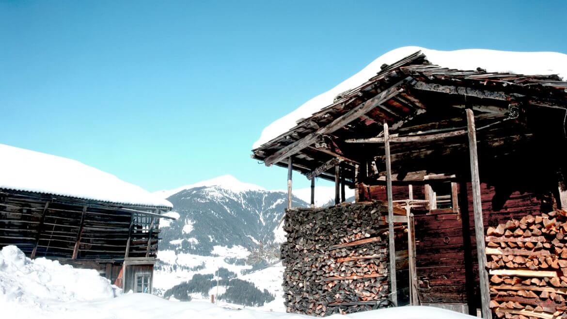 Schneebedeckte Holzhütte mit aufgeschichtetem Holz